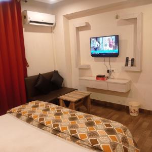 丹巴德的住宿－Hotel Shubh Ashish Near Bank More，一间设有床铺和墙上电视的房间