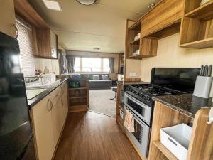 a kitchen with a stove and a living room at Lovely 6 Berth Caravan With Wi-fi At Sand Le Mere In Yorkshire Ref 71091td in Tunstall
