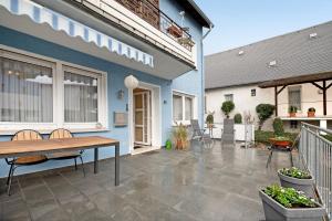 eine Terrasse mit einem Holztisch und einem blauen Haus in der Unterkunft Haus Beate Klein in Kröv