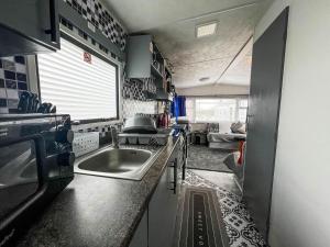 a kitchen with a sink and a living room at Homely Caravan At Sand Le Mere Holiday Park Ref 71018n in Tunstall