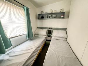 2 camas en una habitación pequeña con ventana en Homely Caravan At Sand Le Mere Holiday Park Ref 71018n, en Tunstall
