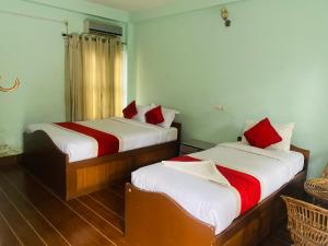 2 Betten in einem kleinen Zimmer mit roter und weißer Bettwäsche in der Unterkunft Eco Adventure Resort in Sauraha