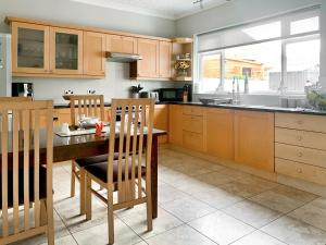 uma cozinha com armários de madeira e uma mesa com cadeiras em Joenina em Bridlington