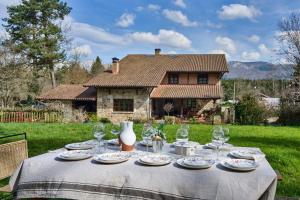 una mesa con platos y copas de vino y una casa en The Basque Experience by Fidalsa, en Ochandiano