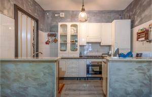 een keuken met witte kasten en marmeren aanrechtbladen bij 2 Bedroom Nice Apartment In San Nicandro Garganico in San Nicandro Garganico