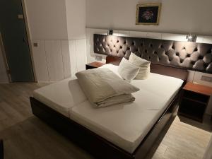 ein großes Bett mit weißer Bettwäsche und Kissen darauf in der Unterkunft Hotel Haase in Hannover
