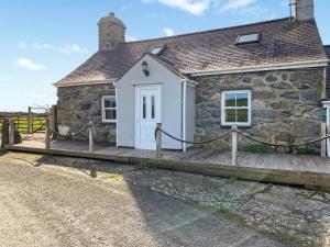 a small stone cottage with a wooden deck at Cyll Y Felin Fawr 1 in Aberdaron