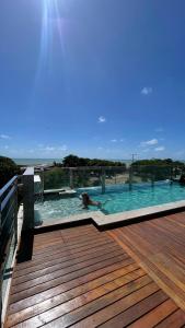 a person in a swimming pool on a wooden deck at Israel flat tambau 106 in João Pessoa