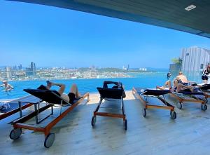 a group of people laying in lounge chairs on the roof of a building at The Base Prime in Pattaya Central