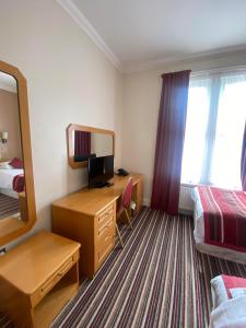 um quarto de hotel com uma secretária e uma cama em The Lawn Hotel em Reading