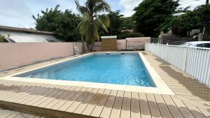 una piscina en un patio trasero con una valla en Ti Caraïbes, appartement T3 atypique, vue mer, piscine et proche plage, en Les Trois-Îlets