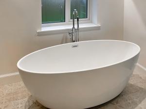bañera blanca con grifo en el baño en Bayview Byre, en Knock