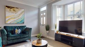 uma sala de estar com um sofá verde e uma televisão de ecrã plano em Castle Boulevard Nottingham - 5 Beds Home - Long stays welcome for families, professionals & contractors em Nottingham