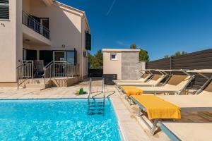 ein Swimmingpool mit Stühlen und ein Haus in der Unterkunft Villa Kristina ZadarVillas in Zaton
