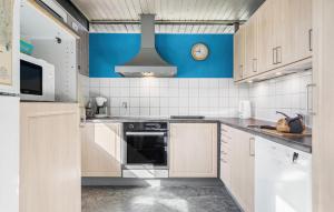 uma cozinha com armários brancos e um relógio na parede em Four-Bedroom Holiday Home In Hemmet em Hemmet