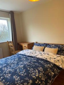 a bedroom with a bed with a blue comforter and a window at Highly Comfortable Home in Hatfield