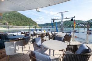 eine Terrasse mit Tischen und Stühlen auf einem Boot in der Unterkunft Thurgau Gold - Art Basel Riverboat Hotel I in Basel