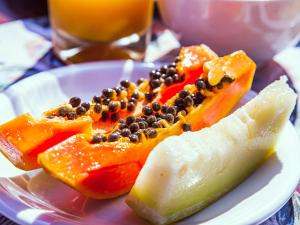 um prato de frutos com sementes e uma fatia de melão em VELINN Pousada Canoa Ilhabela em Ilhabela