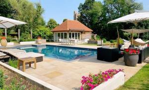 a swimming pool with chairs and an umbrella and a house at Spinster's Nook in Smarden