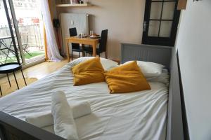 uma cama com lençóis brancos e almofadas amarelas num quarto em Les Maisons Acajou - Ivry-sur-Seine em Ivry-sur-Seine