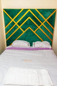 un letto bianco con due cuscini e una parete verde di Enk apartments a Nairobi