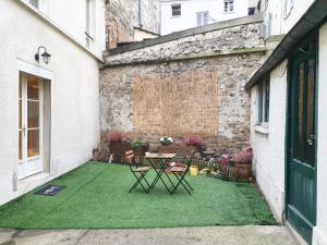 a patio with a table and chairs on a green lawn at EXIGEHOME - Ici habita Voltaire-Maison en plein centre-ville in Saint-Germain-en-Laye