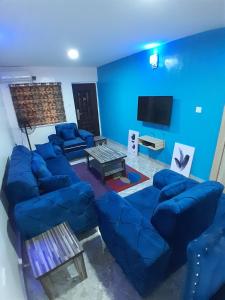 Mofide Queens Apartments (MQA) في Onigbongbo: غرفة معيشة زرقاء مع أرائك وتلفزيون بشاشة مسطحة