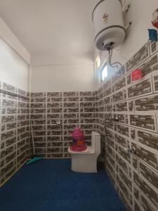 a bathroom with a toilet in a room with brick walls at EVELENA Guest House in Cherrapunji