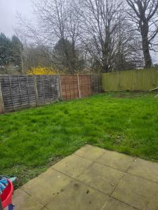 einen Hinterhof mit einem Zaun und einem Rasenplatz in der Unterkunft Highly Comfortable Home in Hatfield