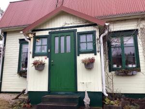 ein kleines Haus mit grüner Tür und Fenstern in der Unterkunft Holiday home HÅVERUD in Håverud