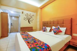 博帕尔FabHotel The Oasis - Maharana Praatap Nagar的卧室配有一张大床,墙上挂着一棵树