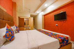 a bedroom with a bed with a tv on the wall at FabHotel The Oasis in Bhopal