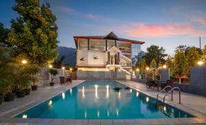 a villa with a swimming pool at night at Summit Green Lake Tea Resort & Spa in Jakhalābāndha