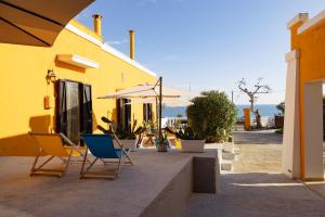 - un groupe de chaises et un parasol à côté d'un bâtiment dans l'établissement CASA LAPILLI, à Polignano a Mare