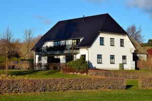 a large white house with a black roof at Inselliebe in Groß Zicker