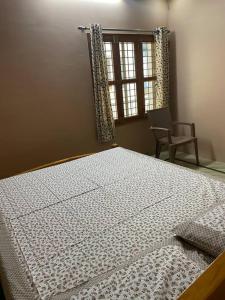 a bed in a room with a window and a chair at Om Sai Nilayam Guest house in Tirupati