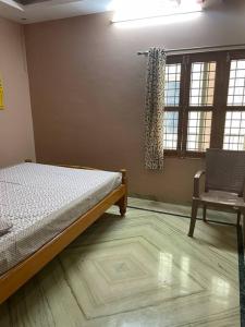 a bedroom with a bed and a chair and a window at Om Sai Nilayam Guest house in Tirupati