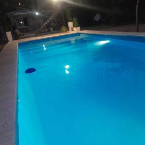 una piscina iluminada por la noche con luces azules en Tierra Santa Estadia 1 en Villa Cura Brochero