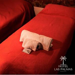 Una toalla está sentada en una cama roja en Las Palmas en Mercedes
