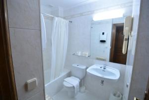 a white bathroom with a toilet and a sink at Ducay Rooms in Olite