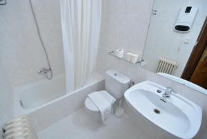 a white bathroom with a toilet and a sink at Ducay Rooms in Olite