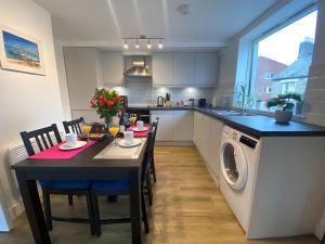 a kitchen with a table with chairs and a washing machine at Cambridge Stays Riverside 2BR Flat-Walk to Centre-Parking-Balcony in Cambridge
