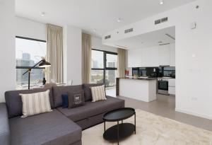 a living room with a couch and a kitchen at Maison Privee - Modern & Panoramic Sea View Apt on Al Reem Island in Abu Dhabi