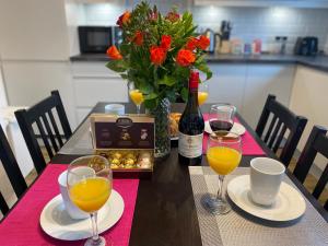 a table with two glasses of orange juice and a bottle of wine at Cambridge Stays Riverside 2BR Flat-Walk to Centre-Parking-Balcony in Cambridge