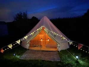 Tienda grande con luces en un campo por la noche en Campsite with Gypsy Vardo Bell Tent, en Loré