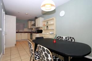 a kitchen with a black table and some chairs at Beautiful 5 Bed Detached House - Sleeps 9 in Peterborough