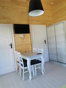 a white table and chairs in a room with doors at Domki Pod Szyszką in Rowy