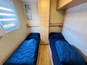 een kleine kamer met 2 bedden en een raam bij RBR 813 - Beach Resort Kamperland in Kamperland