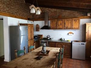 eine Küche mit einem Holztisch und einem Kühlschrank in der Unterkunft Casa y Quincho La Armonia in Barrio Los Zarzales