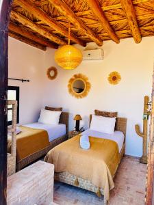 two beds in a room with wooden ceilings at Kasbah Isfoula and Spa in Aït Benhaddou